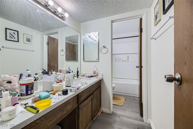 full bathroom featuring vanity, shower / tub combination, toilet, a textured ceiling, and wood-type flooring