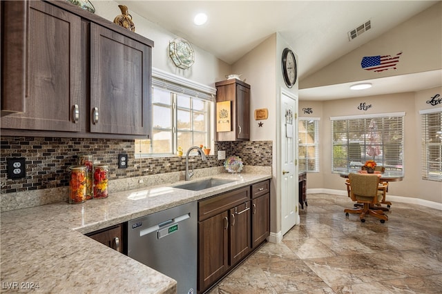 kitchen featuring sink, vaulted ceiling, dishwasher, backsplash, and light stone countertops