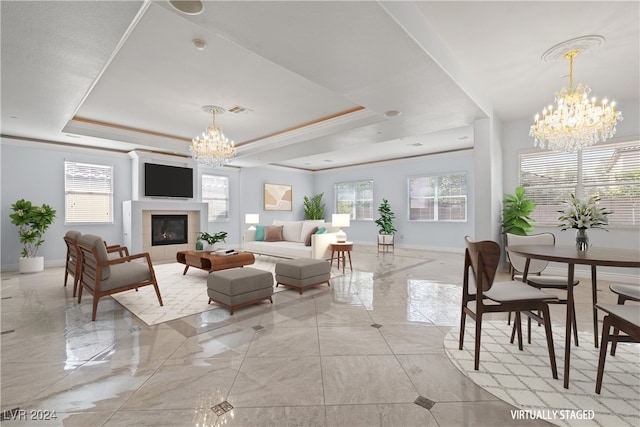 living room featuring a tray ceiling, an inviting chandelier, crown molding, and a fireplace