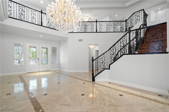 foyer entrance featuring a high ceiling, french doors, and a notable chandelier