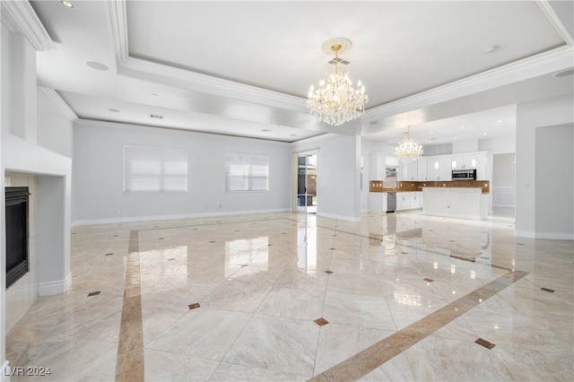 living room with ornamental molding, plenty of natural light, a notable chandelier, and a raised ceiling