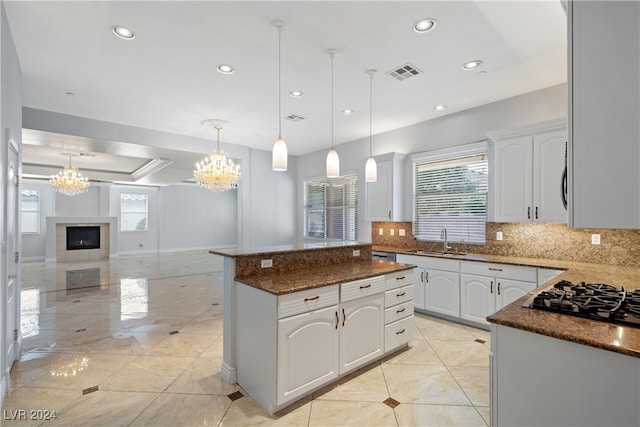 kitchen featuring sink, hanging light fixtures, dark stone countertops, a kitchen island, and white cabinets