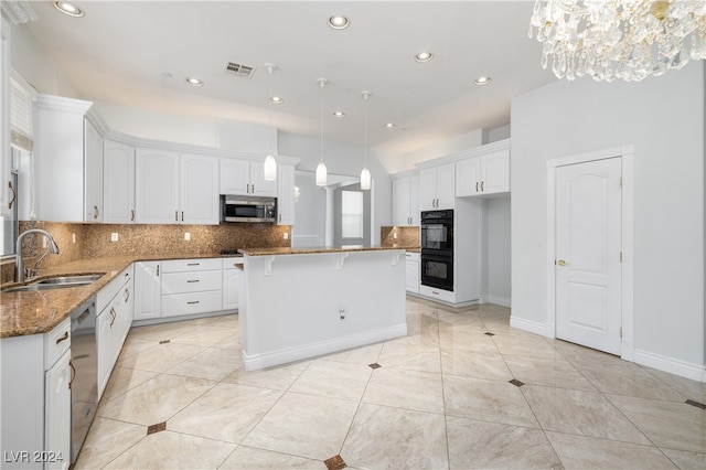 kitchen with white cabinetry, sink, dark stone countertops, a center island, and stainless steel appliances