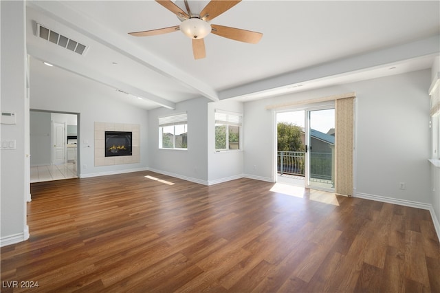 unfurnished living room featuring dark hardwood / wood-style flooring, ceiling fan, a tile fireplace, and lofted ceiling with beams