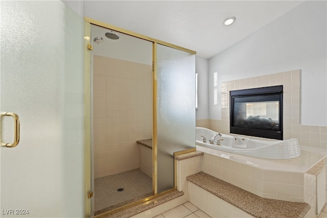 bathroom with a tiled fireplace, tile patterned floors, and independent shower and bath