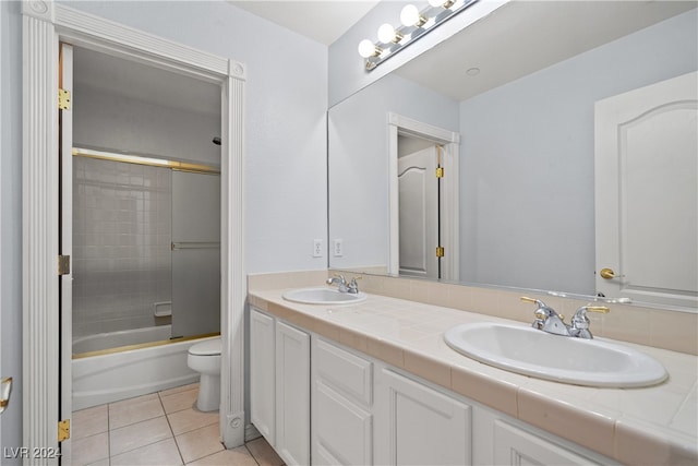 full bathroom with toilet, vanity, bath / shower combo with glass door, and tile patterned flooring