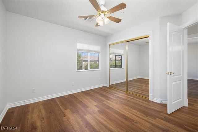 unfurnished bedroom with dark wood-type flooring, a closet, and ceiling fan