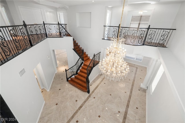 stairway featuring a towering ceiling and ceiling fan with notable chandelier