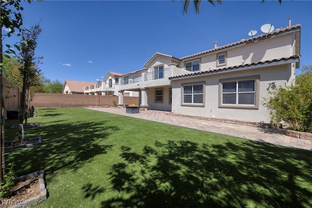 back of house with a balcony, a lawn, and a patio area