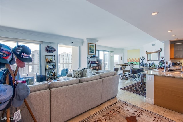 living room featuring crown molding, light tile patterned floors, and sink