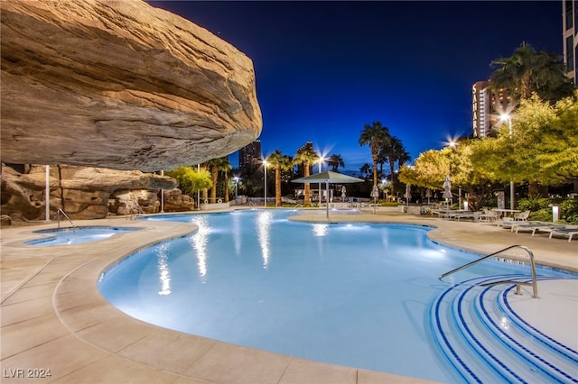 pool at night featuring a patio area