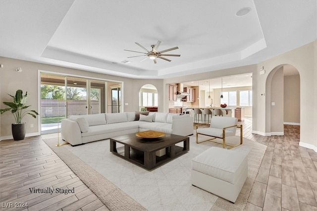 living room featuring light hardwood / wood-style floors, a tray ceiling, and plenty of natural light