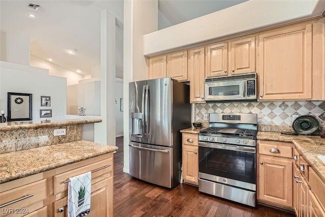 kitchen featuring stainless steel appliances, vaulted ceiling, light stone counters, and dark hardwood / wood-style floors