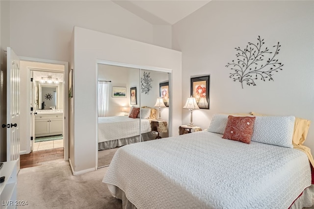 carpeted bedroom featuring a closet, ensuite bath, and lofted ceiling