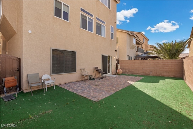 rear view of house featuring a lawn and a patio