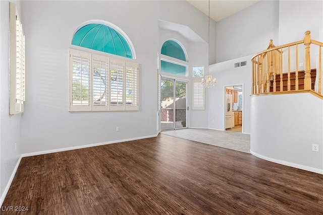 entrance foyer featuring wood-type flooring, a notable chandelier, and a towering ceiling