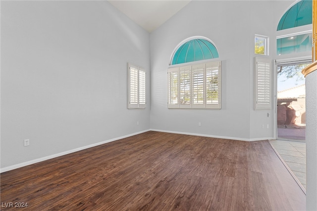 unfurnished room with hardwood / wood-style flooring and high vaulted ceiling