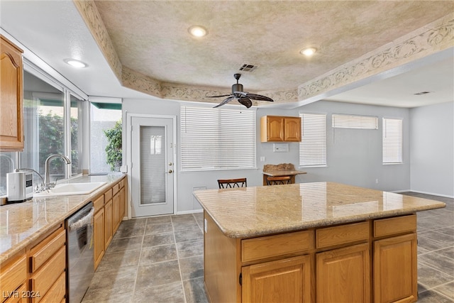 kitchen featuring ceiling fan, sink, dishwasher, a center island, and light stone countertops