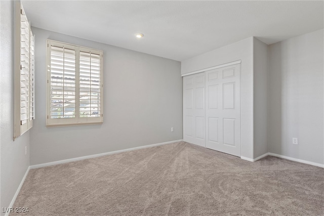 unfurnished bedroom with light carpet and a closet