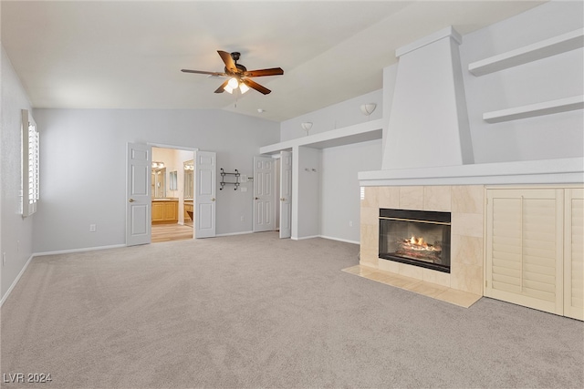 unfurnished living room featuring ceiling fan, lofted ceiling, a tiled fireplace, and light carpet