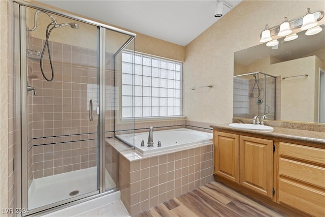 bathroom with plus walk in shower, hardwood / wood-style flooring, and vanity