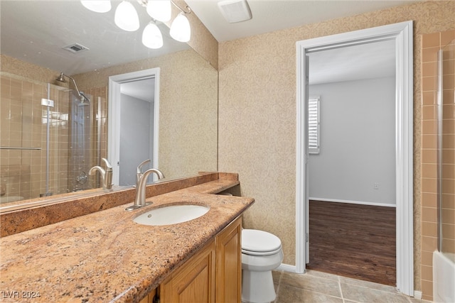 bathroom featuring a tile shower, hardwood / wood-style flooring, vanity, and toilet