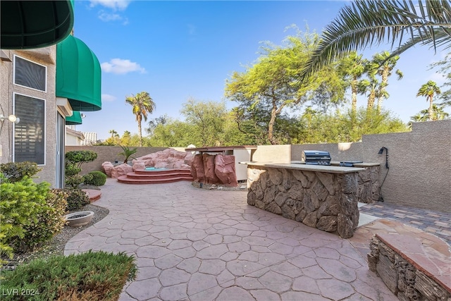 view of patio featuring an outdoor kitchen and a grill