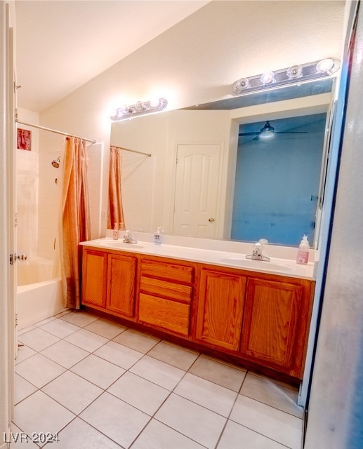 bathroom with vanity, shower / tub combo with curtain, vaulted ceiling, and tile patterned floors