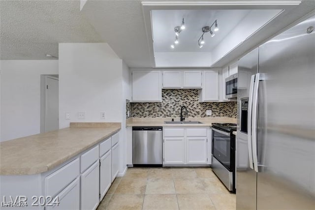 kitchen featuring sink, kitchen peninsula, appliances with stainless steel finishes, backsplash, and white cabinets