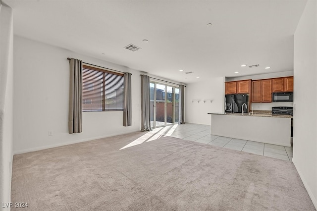 unfurnished living room featuring light carpet and sink