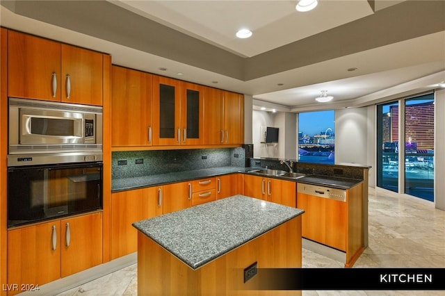 kitchen featuring dark stone countertops, kitchen peninsula, stainless steel appliances, a center island, and sink