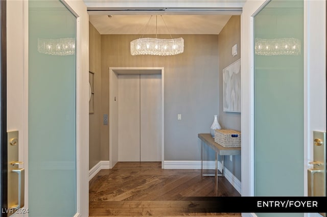 foyer entrance with an inviting chandelier and dark hardwood / wood-style flooring