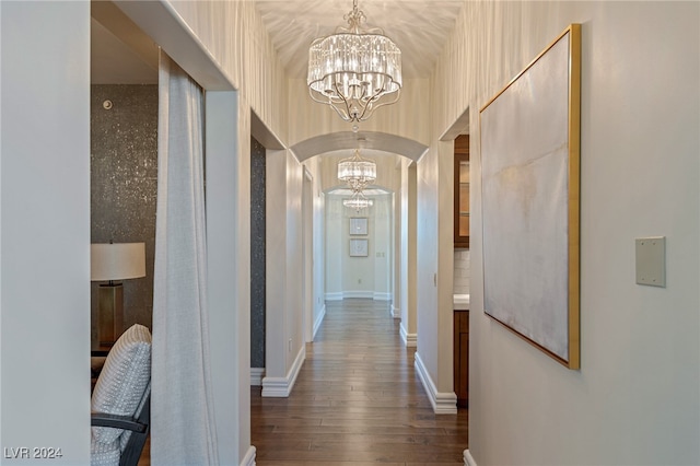 corridor featuring dark hardwood / wood-style floors and an inviting chandelier