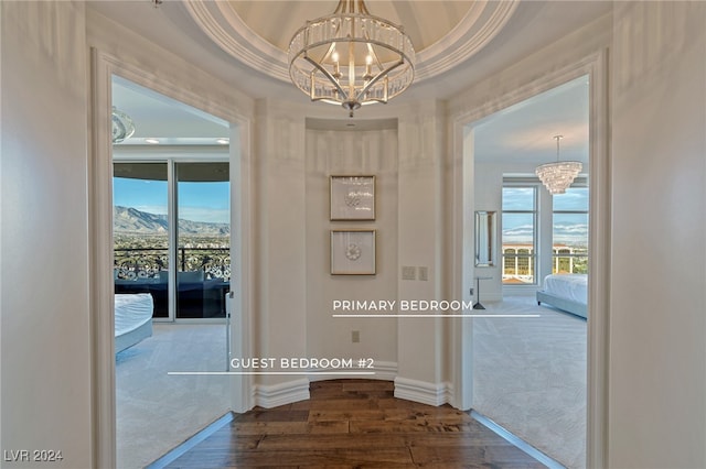 corridor featuring a notable chandelier, dark carpet, and a raised ceiling