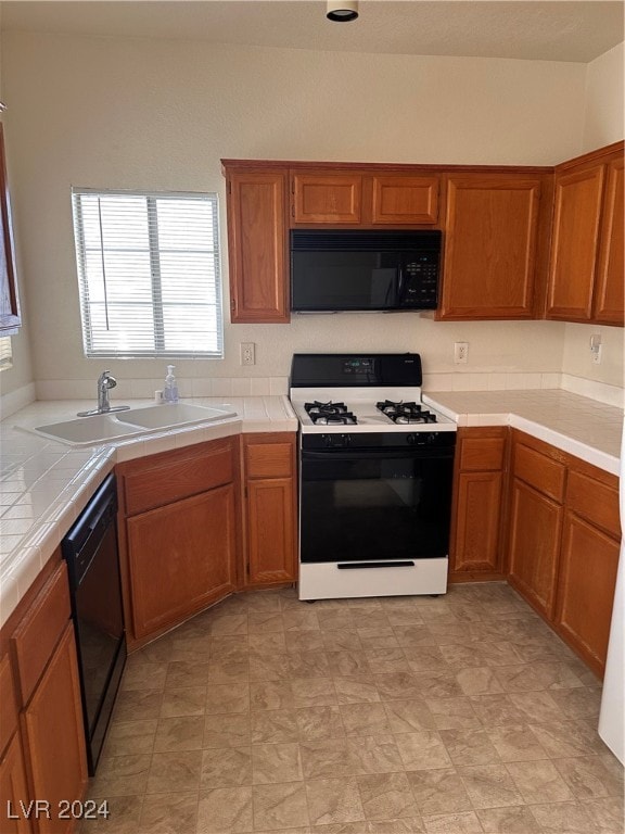 kitchen with tile counters, sink, and black appliances