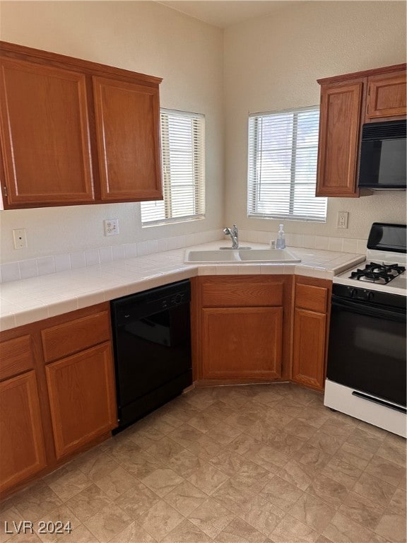 kitchen with black appliances, sink, and tile countertops