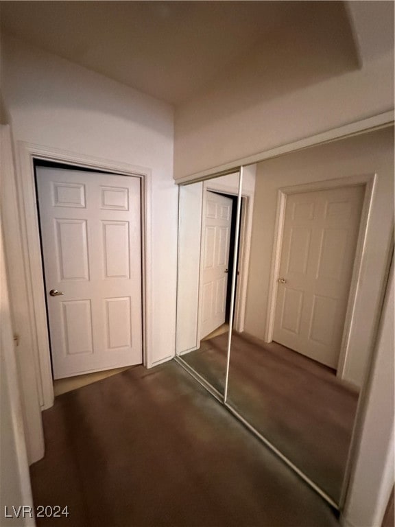 unfurnished bedroom with a closet and dark colored carpet