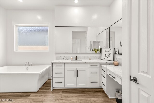 bathroom with a bath, wood-type flooring, and vanity