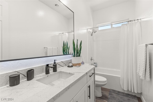 full bathroom featuring vanity, toilet, hardwood / wood-style flooring, and shower / tub combo with curtain