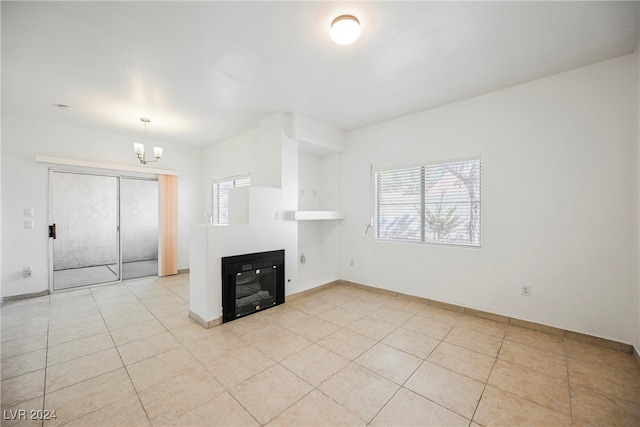 unfurnished living room with an inviting chandelier and light tile patterned floors