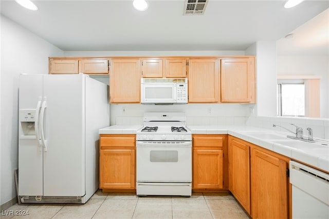 kitchen with white appliances, tile counters, light tile patterned floors, and sink