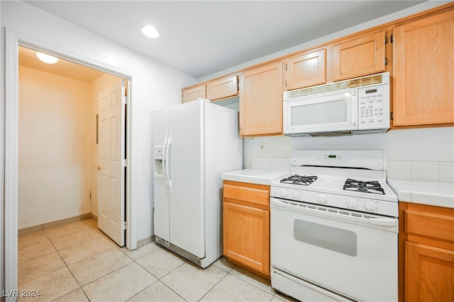 kitchen with white appliances, tile countertops, and light tile patterned floors