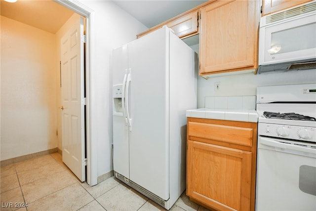 kitchen featuring tile counters, white appliances, light brown cabinets, and light tile patterned floors