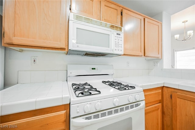 kitchen featuring an inviting chandelier, white appliances, tile counters, and light brown cabinetry