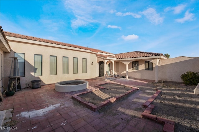 rear view of house featuring a patio area and a fire pit