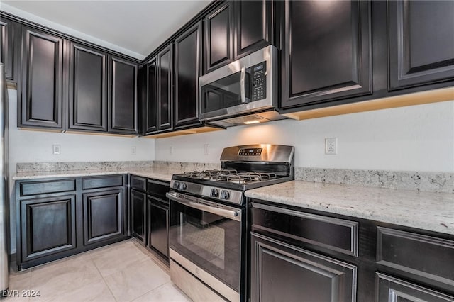 kitchen featuring light stone countertops, stainless steel appliances, and light tile patterned floors