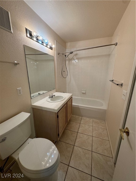 full bathroom with a textured ceiling, tiled shower / bath combo, tile patterned floors, vanity, and toilet