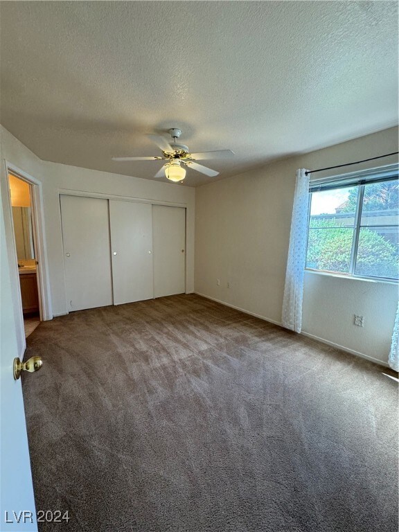 unfurnished bedroom featuring a textured ceiling, ceiling fan, a closet, and carpet floors