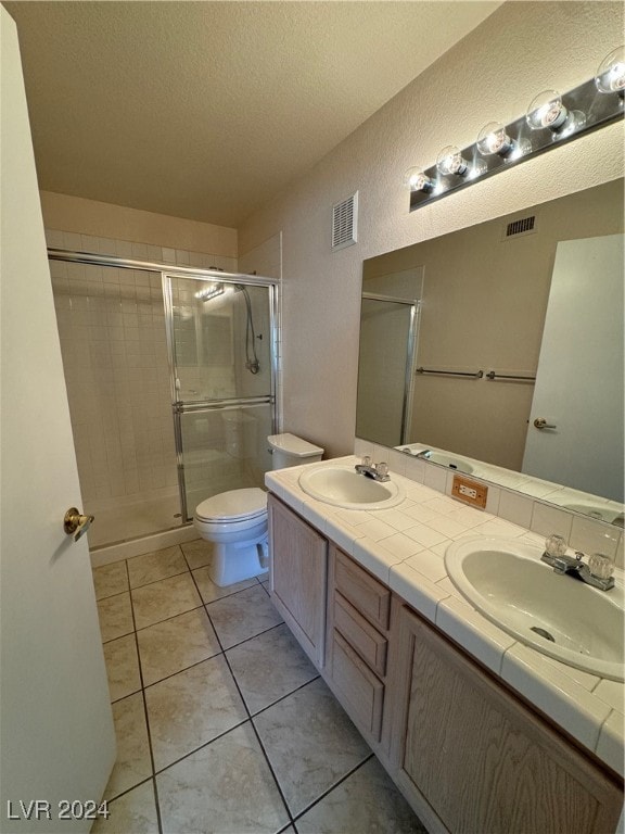 bathroom with vanity, tile patterned flooring, an enclosed shower, a textured ceiling, and toilet