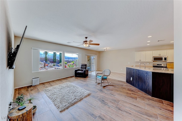 living room with ceiling fan, light hardwood / wood-style flooring, and sink